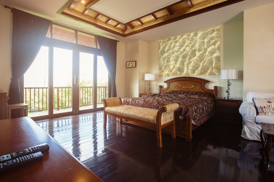 Luxury villa bedroom interior, wooden floor, big windows and balcony