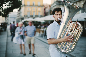 Obraz premium Street musician playing tuba outdoor in European city