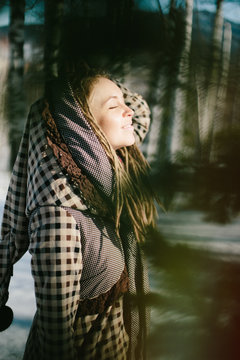 Young woman wearing dreadlocks and boho Coat with large hood enjoy spring day and sun outdoor