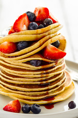 Beautiful Tasty Appetizing Stack Pile of Pancakes with Fresh Summer Fruits and Syrup. Closeup. Bright Background.
