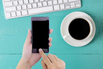 Man hand holding smart phone with white blank empty screen on blue desk table.