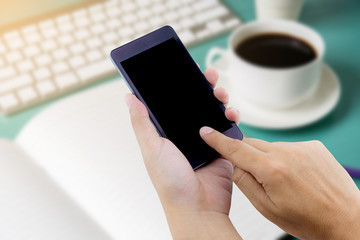 Man hand holding smart phone with white blank empty screen on blue desk table.