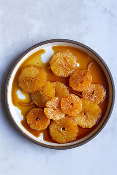 Overhead view of orange slices in syrup against white background