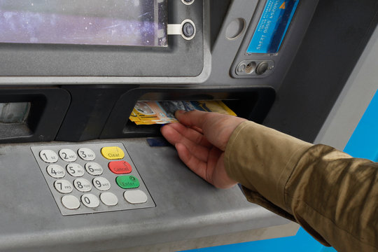 Male hand taking Australian money from an ATM