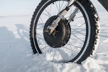 wheel of the electric bicycle on a snow virgin soil
