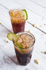 Cola drink with lemon lime in glass on white table