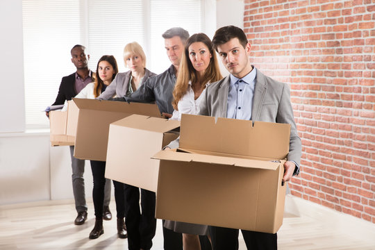 Row Of Businesspeople Standing With Cardboard Boxes