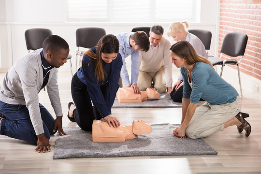 Students Practicing CPR Chest Compression On Dummy