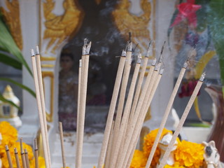 burning incense sticks on blurred background of spirit house with waving smoking