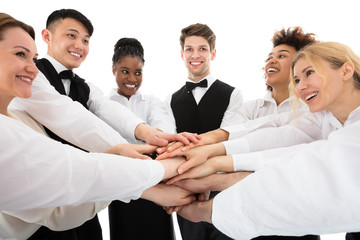 Smiling Young Restaurant Staff Stacking Hands