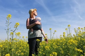 Mother with wraped child in a field.