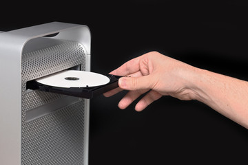 Inserting a black CD / DVD into a gray computer. Hand insert
