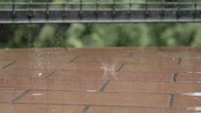 Raindrops falling on balcony floor in slow motion