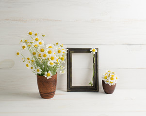 Daisy bouquet in clay vase and photo frame