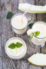 Yogurt and smoothie with melon on a wooden table.