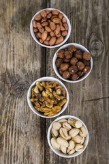 Four bowls with nuts on a  wooden table