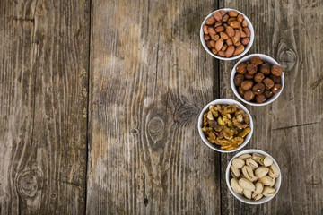 Four bowls with nuts on a  wooden table