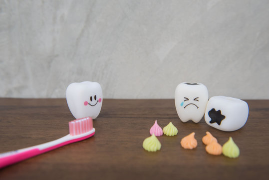 Model Cute toys teeth and colorful candy in dentistry on a wooden table and wall gray background.