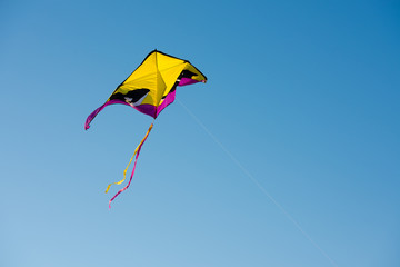 Yellow and purple kite flying in a clear sky