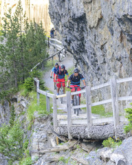 Mountainbiker befahren einen schmalen Pfad entlang einer Felswand