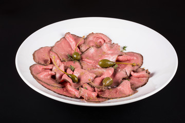 Plate of cold cuts with capers.Cutting meat on a plate with capers
