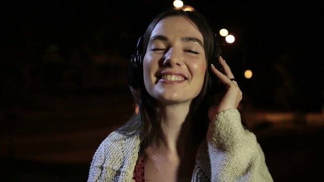 Beautiful woman enjoying music in night city