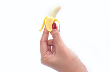 The woman's hand holding a small ripe banana, isolated on a white background