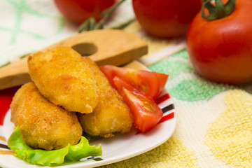 tray of croquettes filled with meat accompanied by tomato and wooden cutlery.
