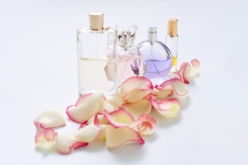 Perfume bottles with flower petals on light background. Perfumery, fragrance collection. Women accessories.