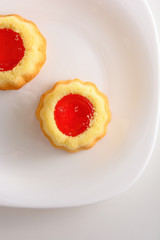 couple of the cookies with strawberry jam on the white plate. Time of tea