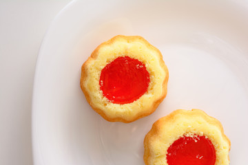 couple of the cookies with strawberry jam on the white plate. Time of tea