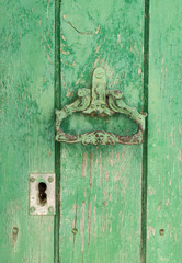 Closeup vintage antique Wooden door painted in worn green on a Country house door lock door handle and latch