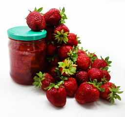 Ripe red strawberries and a jar of strawberry jam on a white background. 