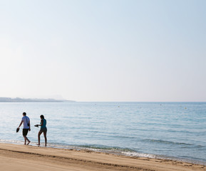 Romantic couple walking along a beach at sunset. Selective focus.