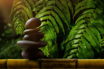 Balance concept between of Life and work present by stack of natural zen rock stone on bamboo...