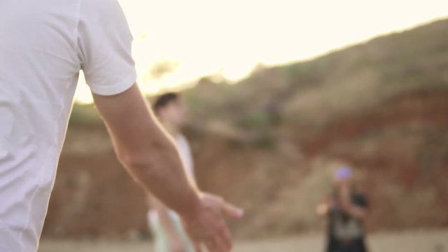 Volleyball player kicking a ball. Joyful young friends playing volley ball on the beach by the sea in the evening. Active vacation. Slowmotion shot