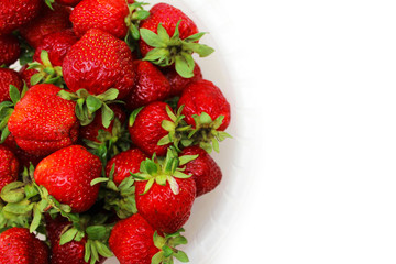 Ripe red strawberries in a dish on a white background