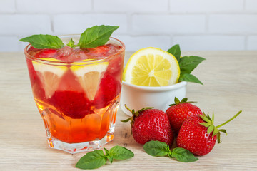 Glass of cold tea with mint,strawberry,lemon, on table
