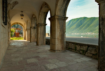 Fototapeta na wymiar The city of Perast in Montenegro. Arches of the museum overlooking the river and mountains