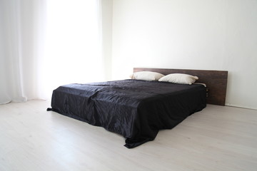 Interior white bedroom and bed with black sheets