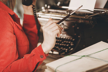 Secretary at old typewriter with telephone. Young woman using typewriter. Business concepts.