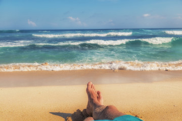 Man enjoying at the beach - focus is on feet. - obrazy, fototapety, plakaty