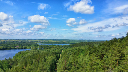 Fototapeta na wymiar Picturesque view on the lake and forest at evening time just before the sunset. Sky and clouds reflected in water surface.Beautiful natural landscape. Panoramic view. The land of lakes. Europe.
