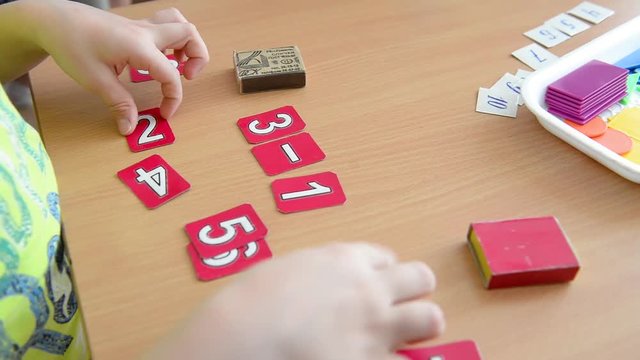 A mathematical example. Child holds a paper figure. Mathematical problem solving in primary school.