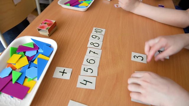 A mathematical example. Child holds a paper figure. Mathematical problem solving in primary school.