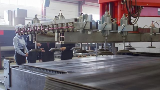 Tracking shot shot of group of engineers standing inside of compressor plant and watching manufacturing process