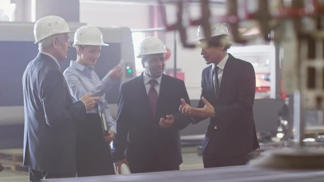 Group of engineers of different ethnicities standing in compressor plant and discussing manufacturing process 