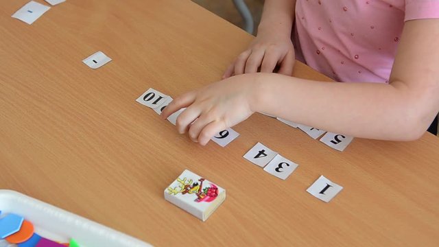 A mathematical example. Child holds a paper figure. Mathematical problem solving in primary school.
