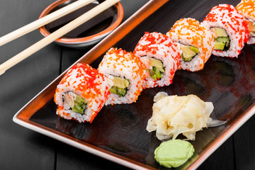 Sushi Roll - Maki Sushi with red caviar, Crab meat, avocado, cucumber and cream cheese on dark wooden background. Top view. Japanese cuisine