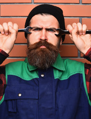 Bearded brutal caucasian mechanic holding metallic wrenches